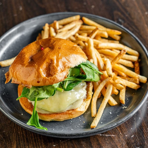 A Steam Pub burger with melted cheese and spinach, served with a side of golden fries.