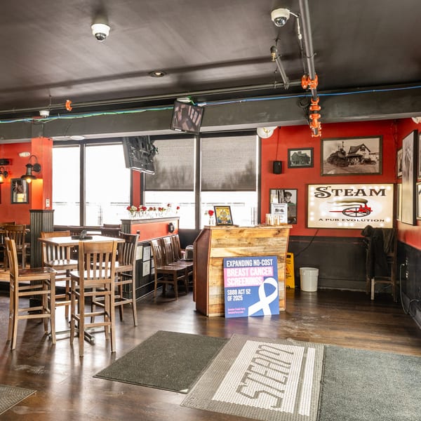 Interior of Steam Pub with high-top tables, red walls, and a large "STEAM A PUB EVOLUTION" sign.