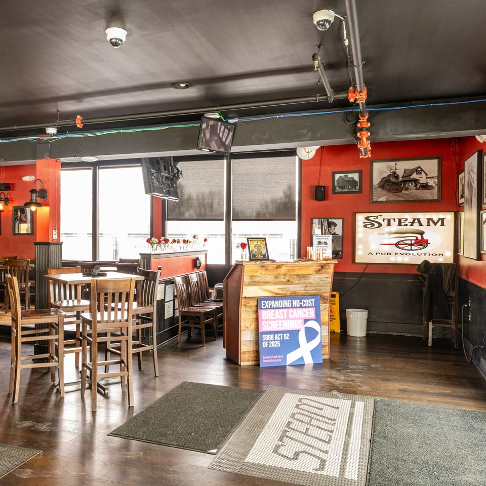 Interior of Steam Pub with high-top tables, red walls, and a large "STEAM A PUB EVOLUTION" sign.